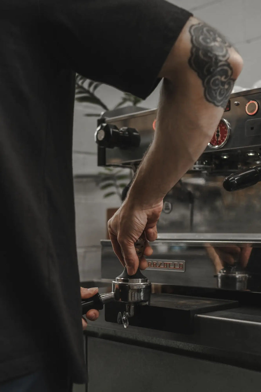 The espresso machine features a sleek stainless steel body with black accents and red illuminated controls.