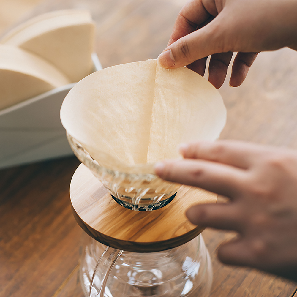 Placing a Hario V60 02 natural paper filter into a V60 dripper before brewing