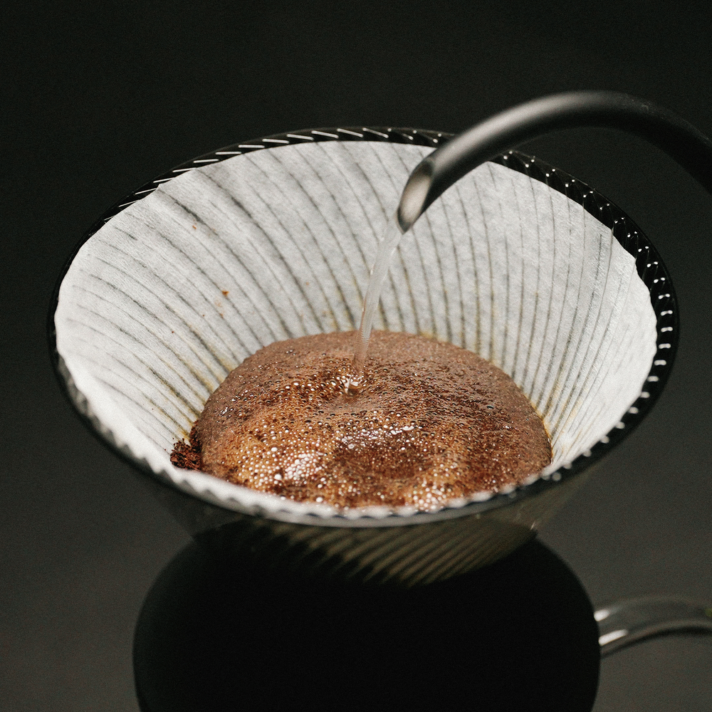 Pouring hot water over a coffee bloom in the Hario V60 NEO 02 dripper